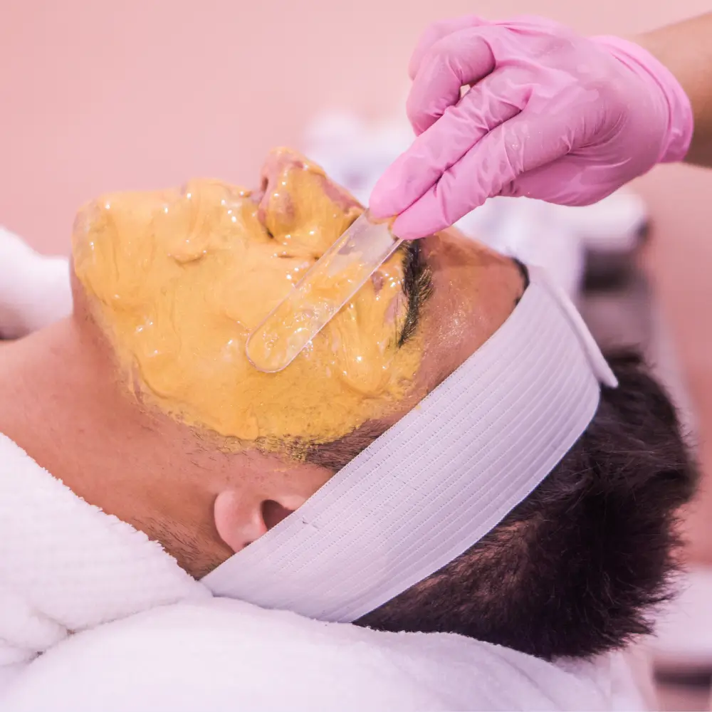 esthetician applies thick firming mask to clients face facial