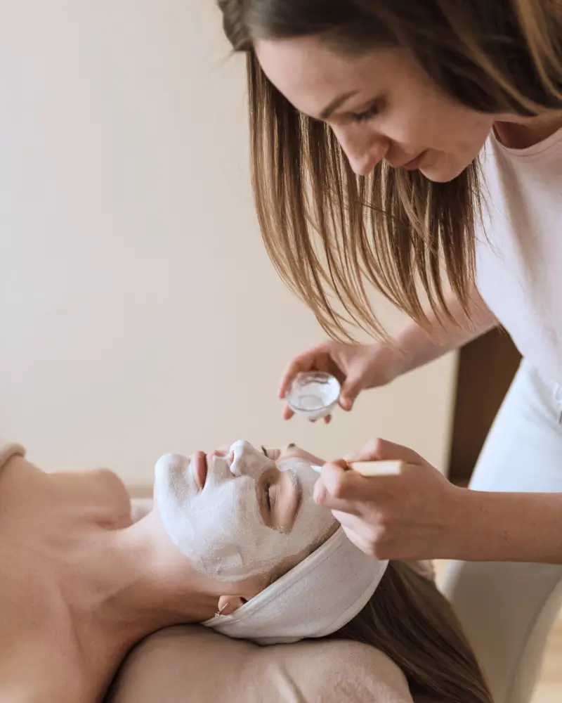 esthetics student in The Maven Method applying a mask to a clients face hands-on experience