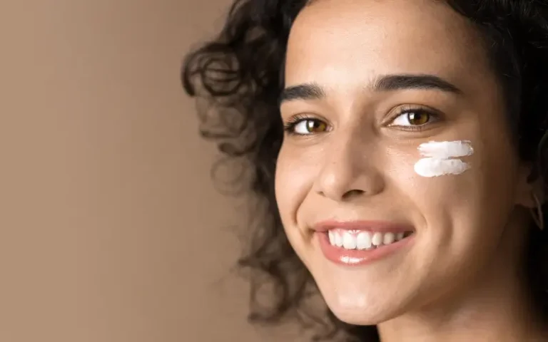 smiling woman with skincare on her cheek to represent our list of comedogenic skincare and makeup ingredients that may clog pores
