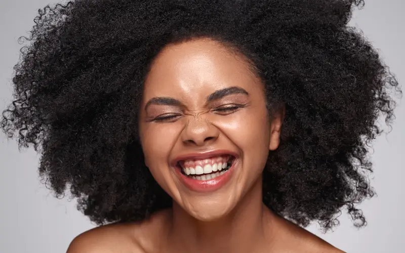 close up of smiling black woman with natural hair and beautiful skin with healthy skin texture and healthy skin barrier