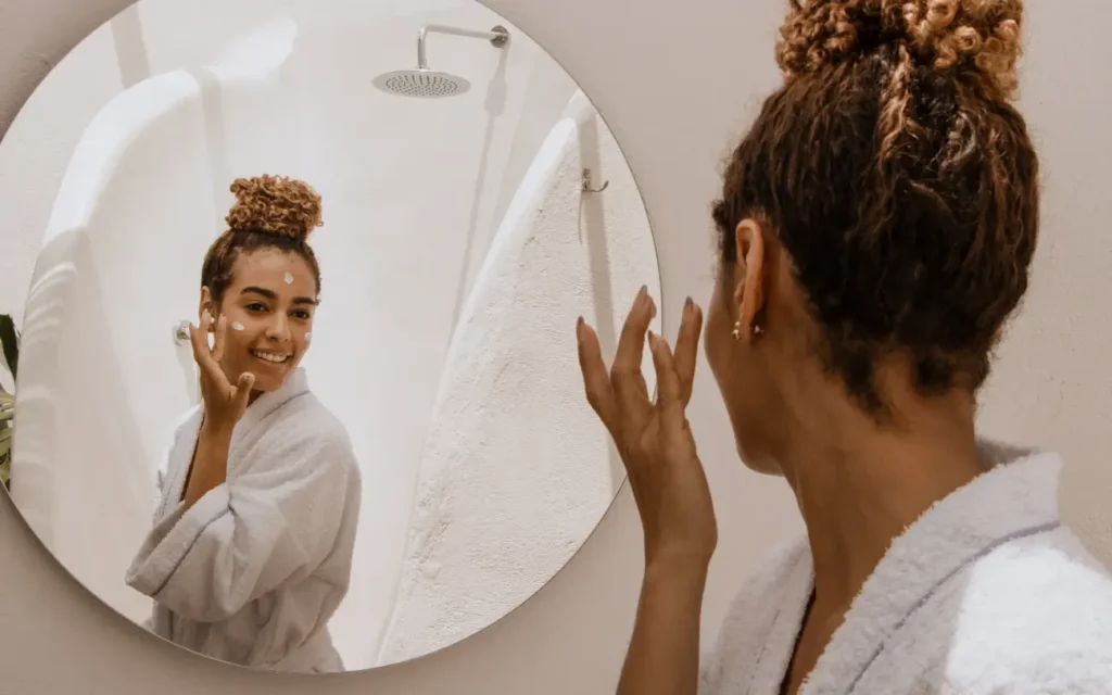 young black woman applying retinol tretinoin looking in the mirror
