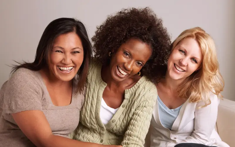 3 mid-life women vibrant laughing diverse skintones representing menopause skin support and confidence.