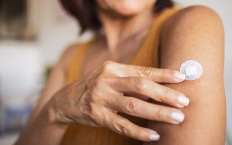 Woman with a hormone patch representing skin changes during menopause and HRT