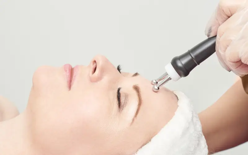 mid-life woman lying on treatment table getting a microcurrent treatment to represent professional firming devices