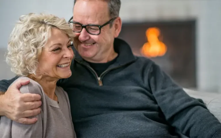 woman going through menopause sitting on the couch embraced by her supportive husband